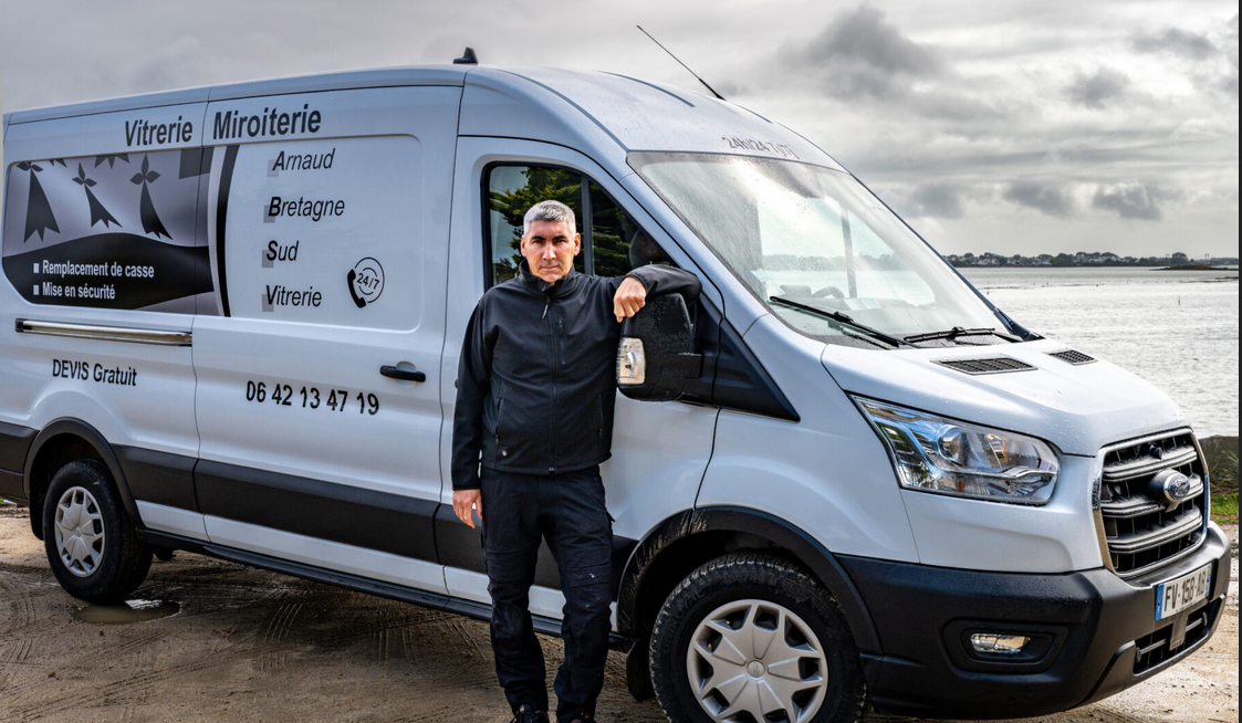 Portrait d'Arnaud Hervo, artisan vitrier-menuisier et fondateur d'ABS Vitrerie, devant son véhicule d'intervention dans le Morbihan.