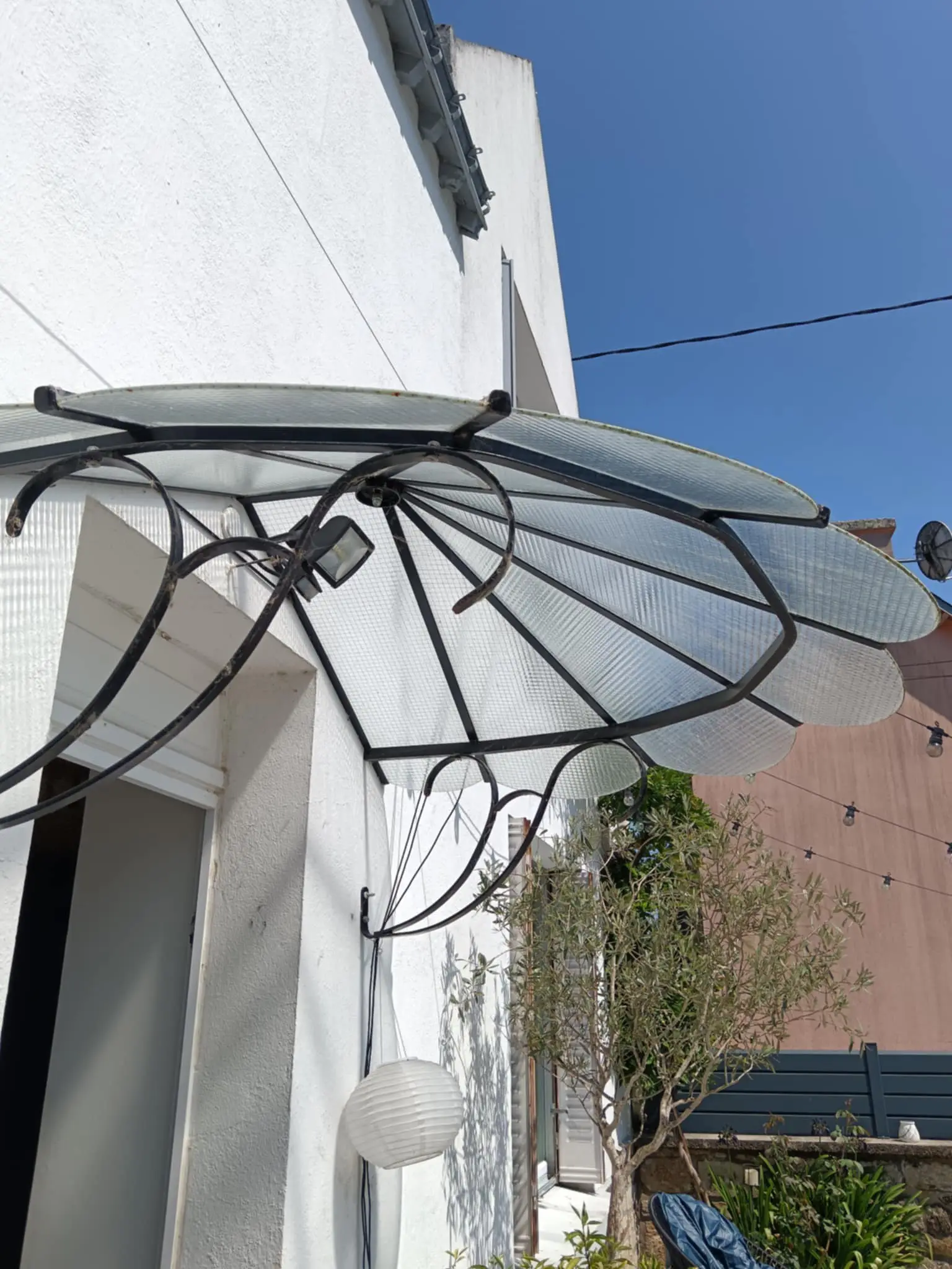 Pose d'une marquise de porte d'entrée de style rétro avec une structure en fer forgé et une couverture en verre armé pour protéger des intempéries.