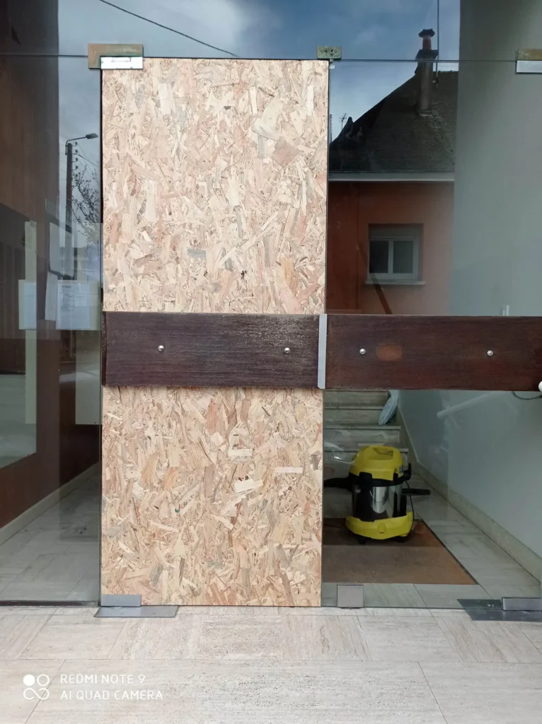 mise-en-securite-porte-vitree-cassee-commerce-morbihan Fermeture provisoire d'une porte de magasin après un bris de glace. La mise en sécurité est réalisée avec des panneaux de bois pour protéger le commerce en attendant le remplacement de la vitrine.