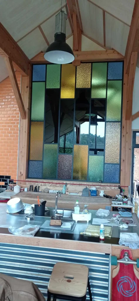 Création d'un grand panneau mural décoratif composé de plusieurs verres colorés et texturés, réalisé sur mesure pour une cuisine d'architecte à Lorient.