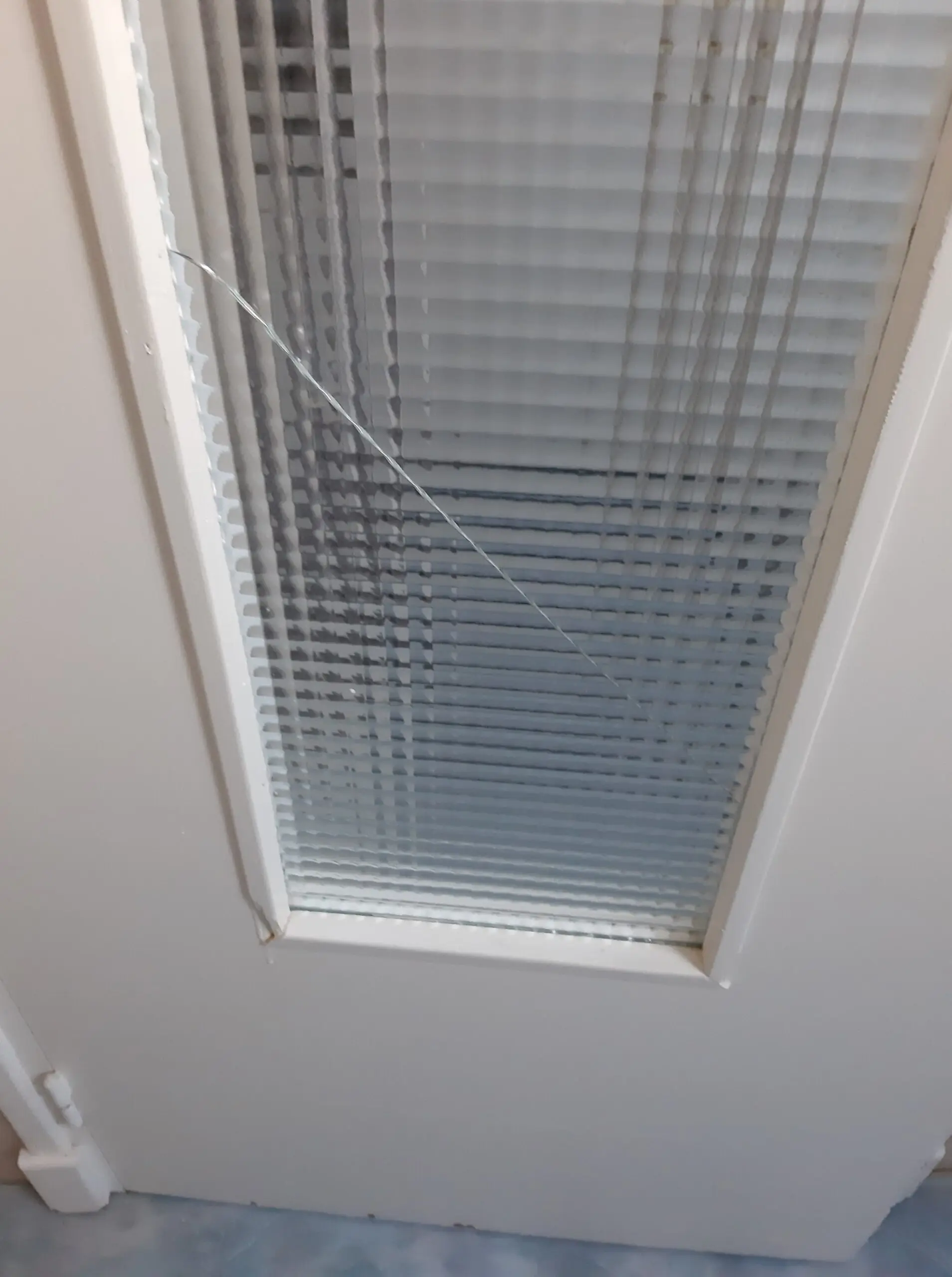 Gros plan sur une vitre de porte intérieure fissurée, nécessitant un dépannage d'urgence et un remplacement de vitrage.